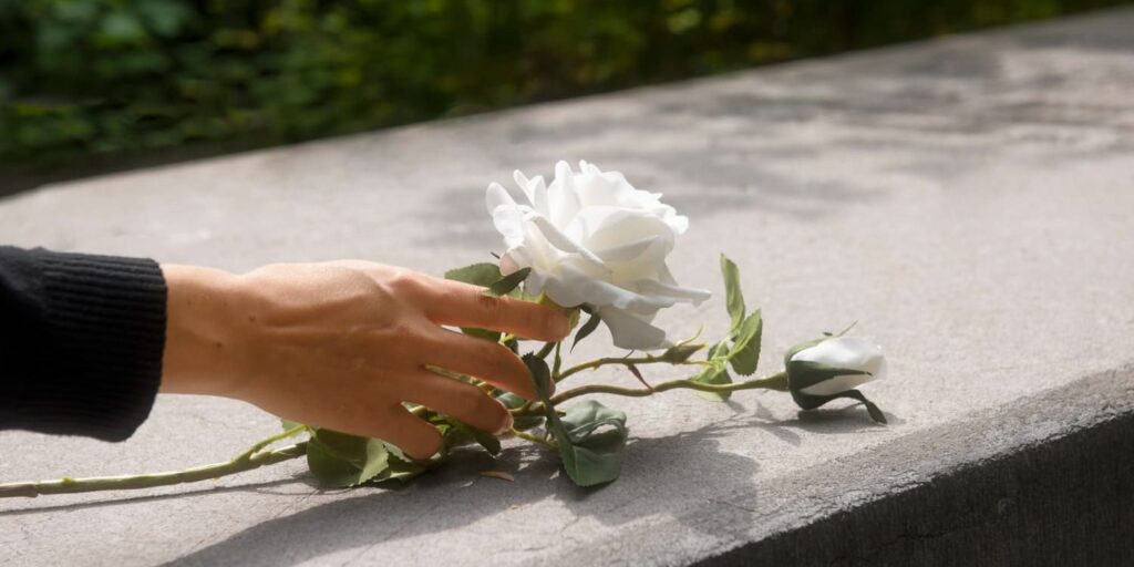 Donazioni in Memoria Mano depone rosa bianca su lapide